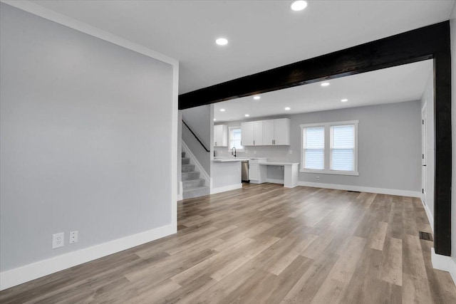 unfurnished living room featuring beam ceiling and light wood-type flooring