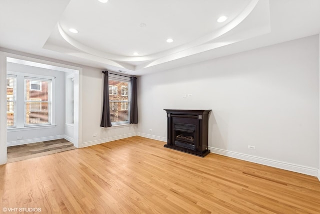 unfurnished room featuring light hardwood / wood-style floors and a tray ceiling