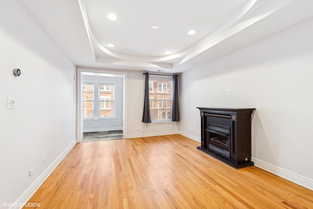 unfurnished room featuring light hardwood / wood-style flooring and a raised ceiling