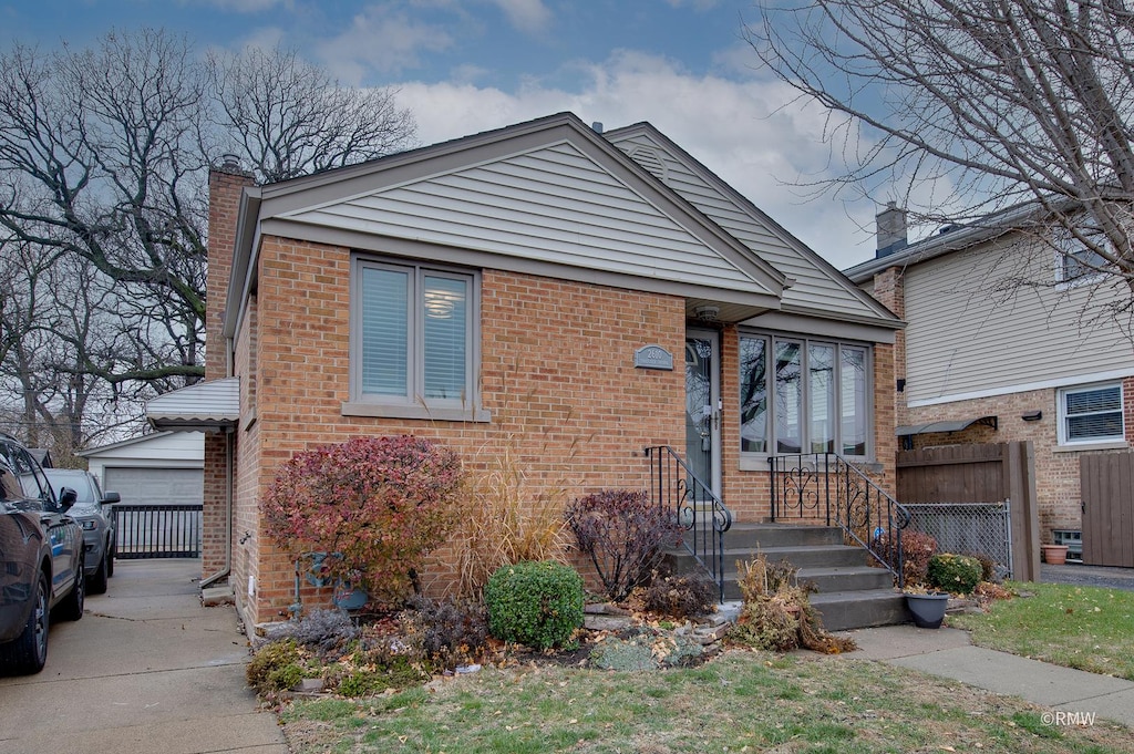 bungalow-style home featuring a garage and an outbuilding