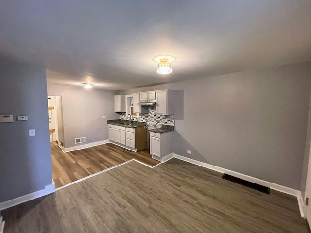 kitchen with backsplash, dark hardwood / wood-style flooring, white cabinetry, and sink