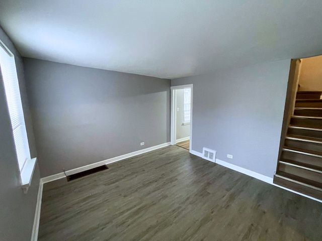 empty room featuring plenty of natural light and dark wood-type flooring