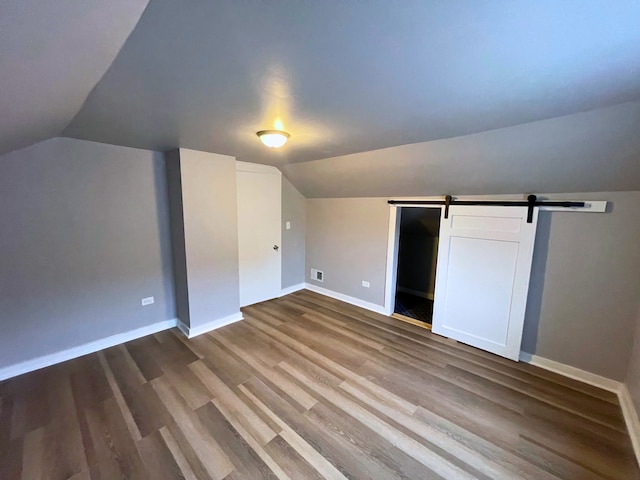 bonus room with a barn door, lofted ceiling, and hardwood / wood-style flooring