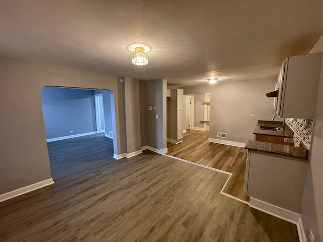 unfurnished living room with dark hardwood / wood-style floors, sink, and a chandelier