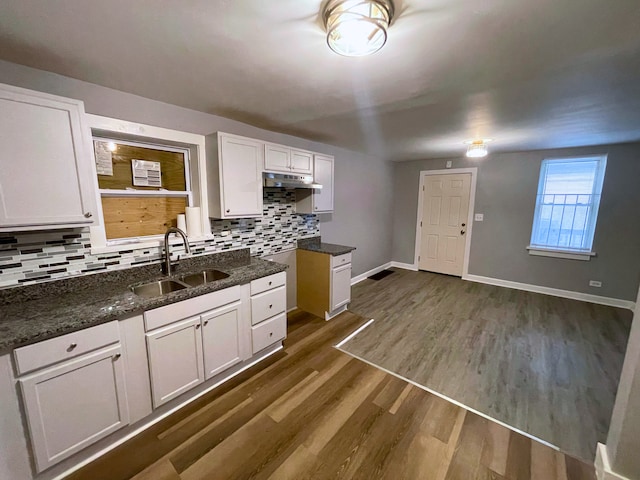 kitchen featuring sink, dark hardwood / wood-style floors, backsplash, dark stone countertops, and white cabinets