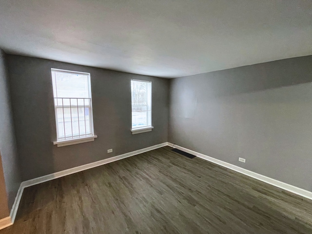 spare room with dark hardwood / wood-style floors and plenty of natural light