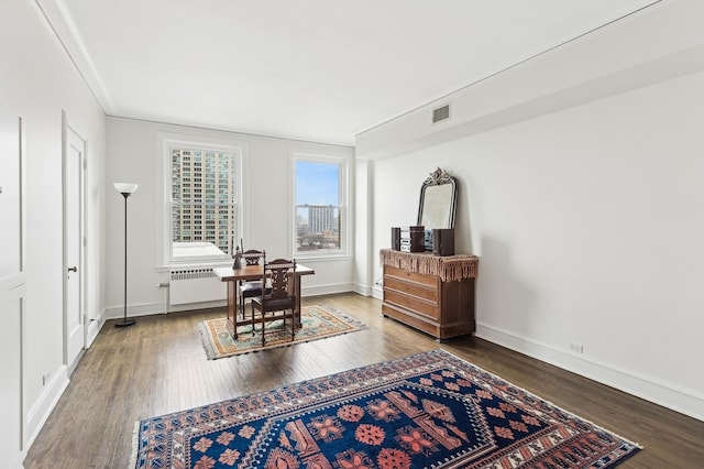 sitting room with hardwood / wood-style flooring, ornamental molding, and radiator heating unit