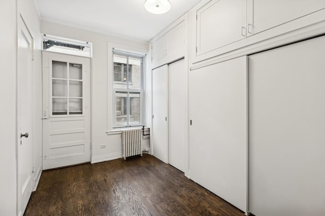 unfurnished bedroom featuring dark wood-type flooring, a closet, radiator heating unit, and ornamental molding