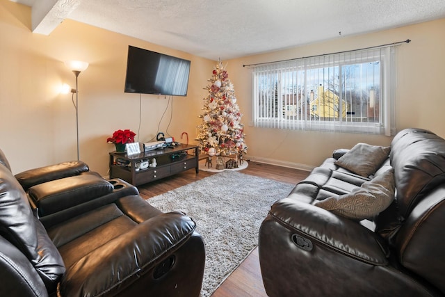 living room with hardwood / wood-style flooring, a textured ceiling, and beamed ceiling