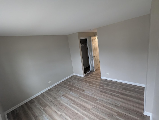 empty room with light hardwood / wood-style floors and lofted ceiling