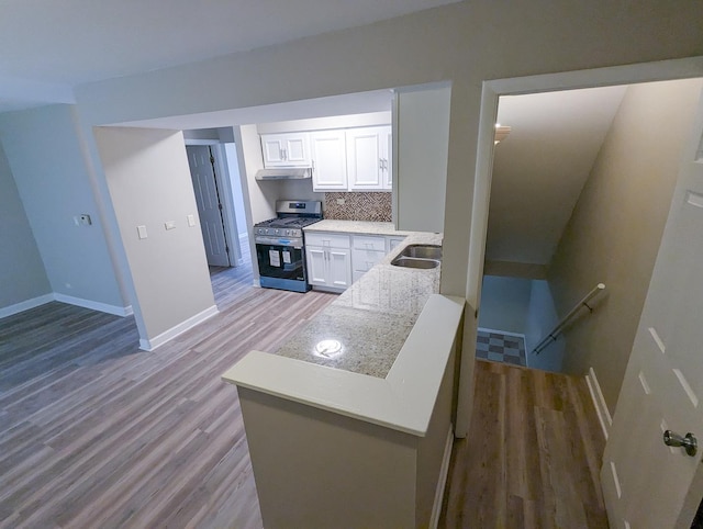 kitchen featuring gas stove, light hardwood / wood-style floors, white cabinetry, and backsplash