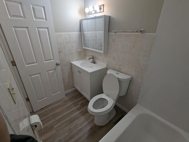 bathroom with hardwood / wood-style floors, vanity, tile walls, and toilet