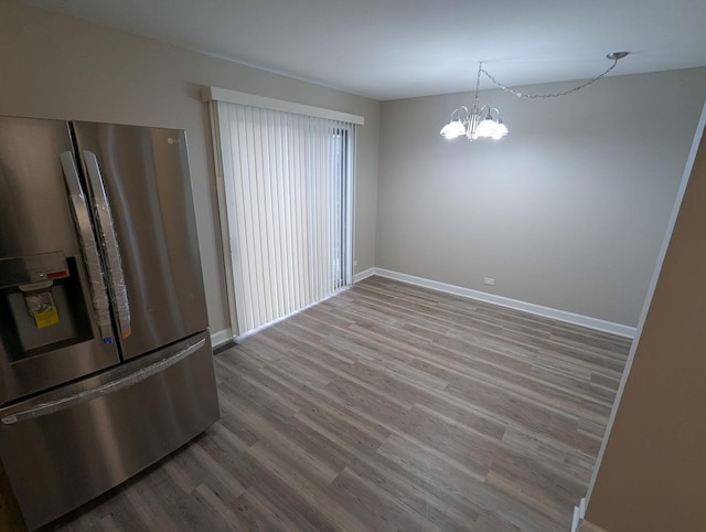 unfurnished dining area featuring wood-type flooring and a notable chandelier