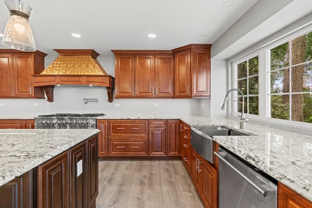 kitchen featuring premium range hood, sink, light stone counters, stainless steel appliances, and light hardwood / wood-style flooring