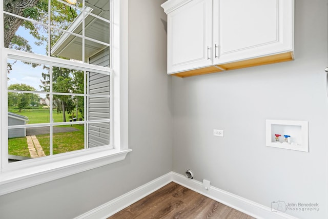 clothes washing area with electric dryer hookup, hookup for a washing machine, dark wood-type flooring, and cabinets