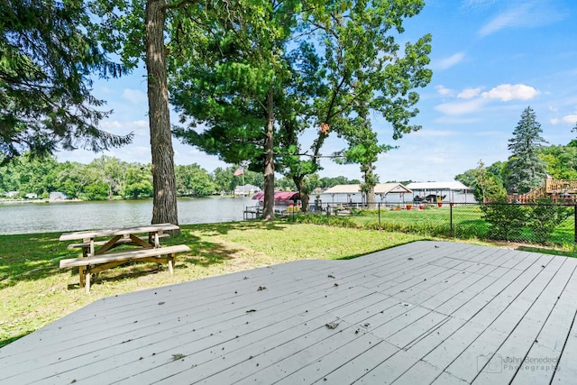 wooden deck featuring a water view and a lawn