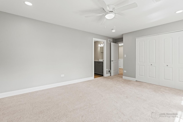 unfurnished bedroom with ceiling fan, a closet, ensuite bath, and light carpet