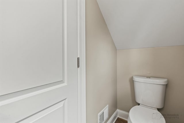 bathroom with lofted ceiling and toilet