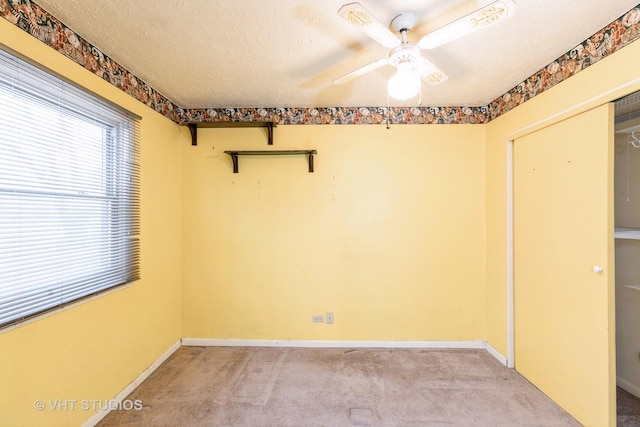 unfurnished room with a textured ceiling, light colored carpet, and ceiling fan