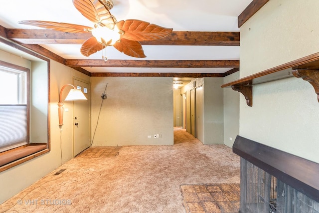 carpeted empty room with beam ceiling and ceiling fan