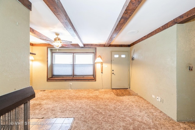 interior space with carpet, ceiling fan, and beamed ceiling