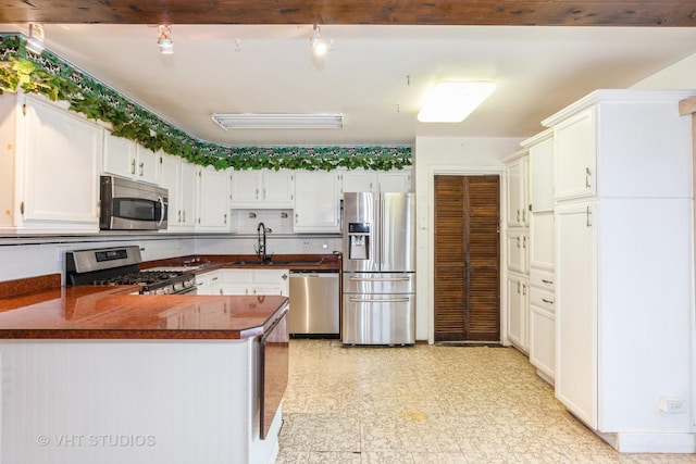 kitchen featuring sink, decorative backsplash, white cabinetry, kitchen peninsula, and stainless steel appliances