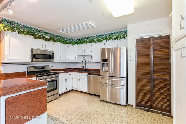 kitchen featuring decorative backsplash, white cabinetry, sink, and appliances with stainless steel finishes