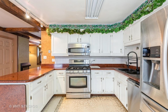 kitchen with track lighting, white cabinets, sink, kitchen peninsula, and stainless steel appliances