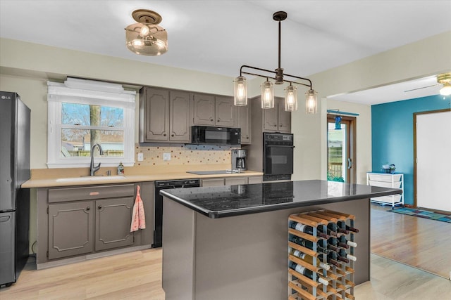 kitchen featuring tasteful backsplash, sink, black appliances, light hardwood / wood-style flooring, and a center island