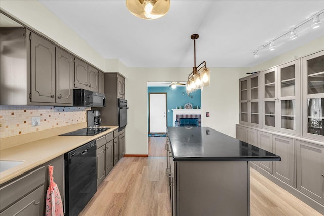 kitchen with light wood-type flooring, tasteful backsplash, ceiling fan, black appliances, and a kitchen island