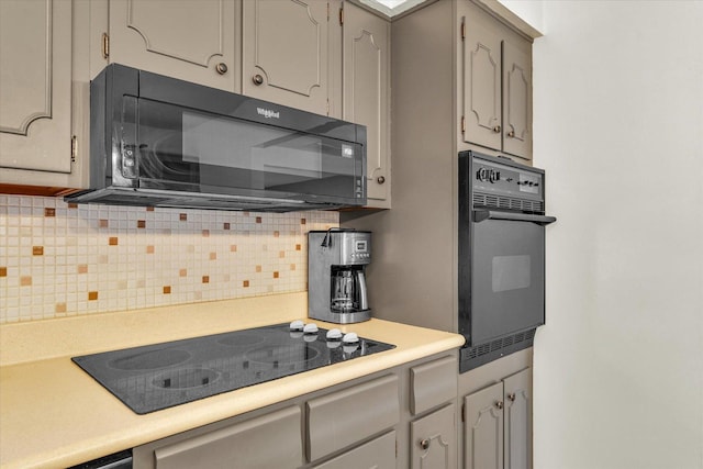 kitchen featuring decorative backsplash, gray cabinets, and black appliances