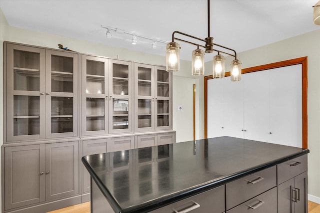 kitchen featuring gray cabinetry, a center island, decorative light fixtures, and light wood-type flooring