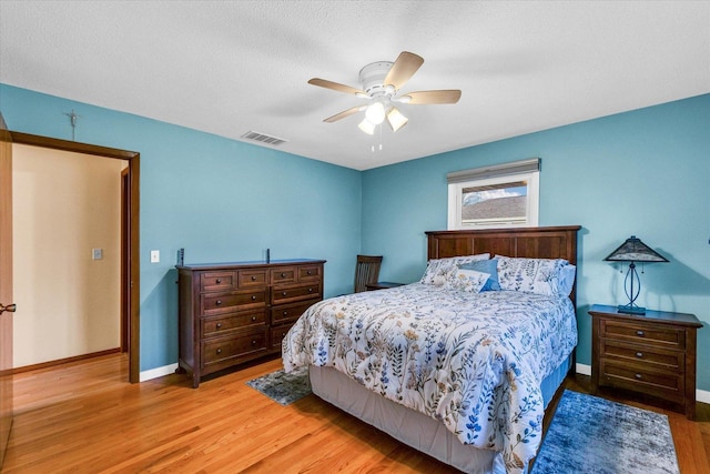 bedroom with ceiling fan, light wood-type flooring, and a textured ceiling