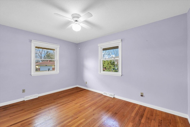 unfurnished room featuring a wealth of natural light, ceiling fan, a textured ceiling, and hardwood / wood-style flooring