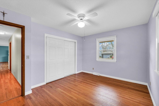 unfurnished bedroom with hardwood / wood-style floors, ceiling fan, a textured ceiling, and a closet