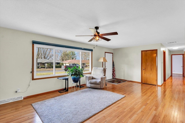 sitting room with a textured ceiling, light hardwood / wood-style floors, and ceiling fan