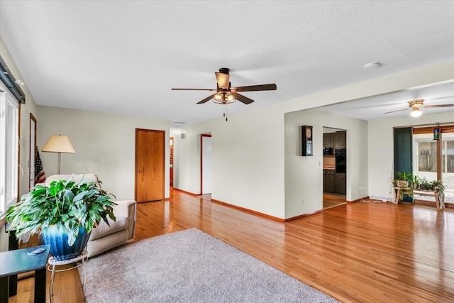 unfurnished living room featuring ceiling fan, wood-type flooring, and a textured ceiling