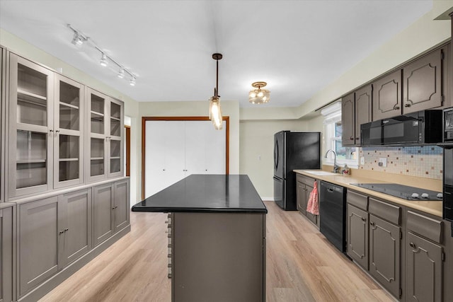 kitchen with a center island, sink, tasteful backsplash, light hardwood / wood-style flooring, and black appliances