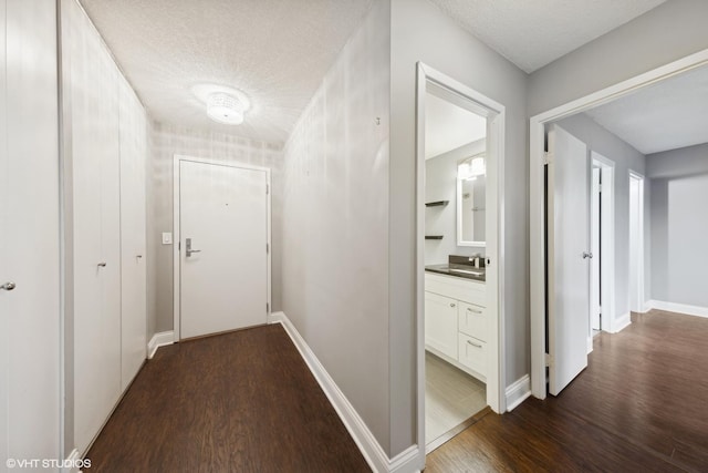 corridor featuring dark hardwood / wood-style floors, sink, and a textured ceiling