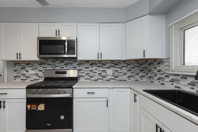 kitchen featuring appliances with stainless steel finishes, tasteful backsplash, white cabinetry, and sink