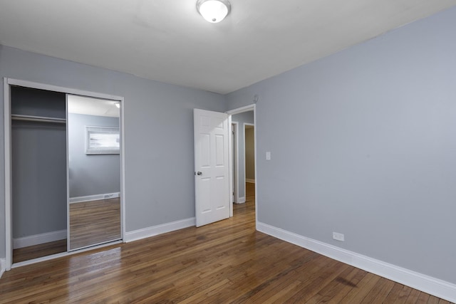 unfurnished bedroom with dark hardwood / wood-style flooring and a closet