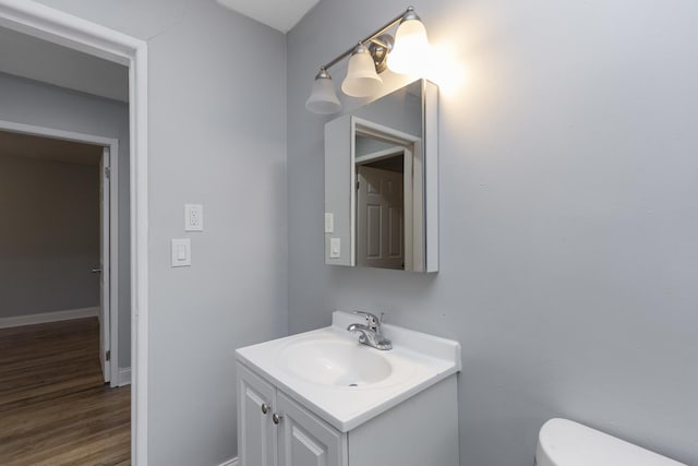 bathroom with hardwood / wood-style flooring, vanity, and toilet