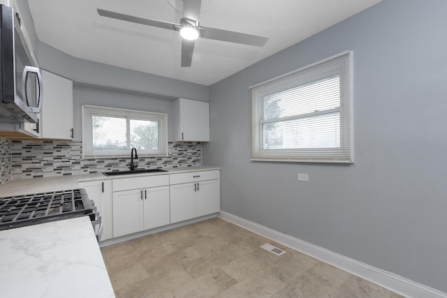 kitchen with tasteful backsplash, sink, white cabinets, and stainless steel appliances