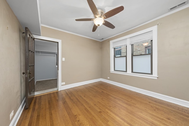 unfurnished bedroom featuring ceiling fan, a closet, wood-type flooring, and ornamental molding