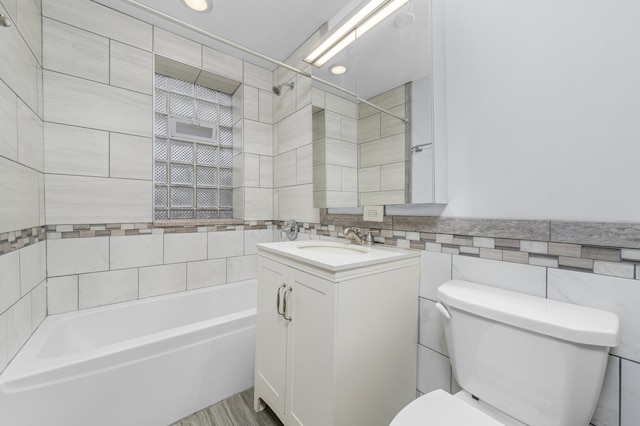 full bathroom with vanity, tiled shower / bath, toilet, tile walls, and wood-type flooring