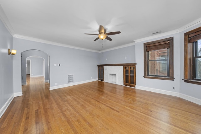 unfurnished living room with ceiling fan, a fireplace, light wood-type flooring, and ornamental molding