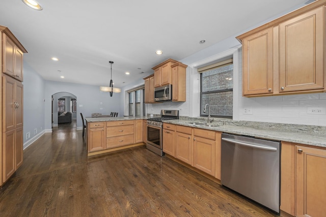 kitchen with sink, hanging light fixtures, stainless steel appliances, dark hardwood / wood-style floors, and kitchen peninsula