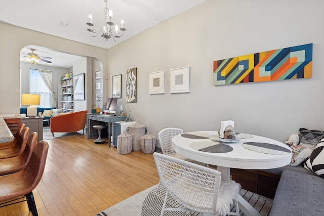 dining area with wood-type flooring and ceiling fan with notable chandelier