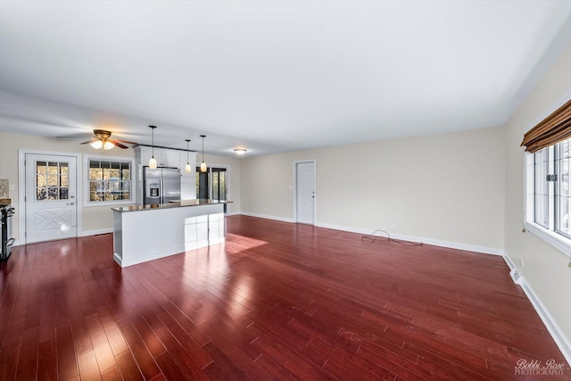 unfurnished living room featuring ceiling fan and dark hardwood / wood-style flooring