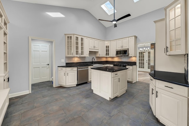 kitchen with backsplash, high vaulted ceiling, ceiling fan with notable chandelier, a skylight, and stainless steel appliances